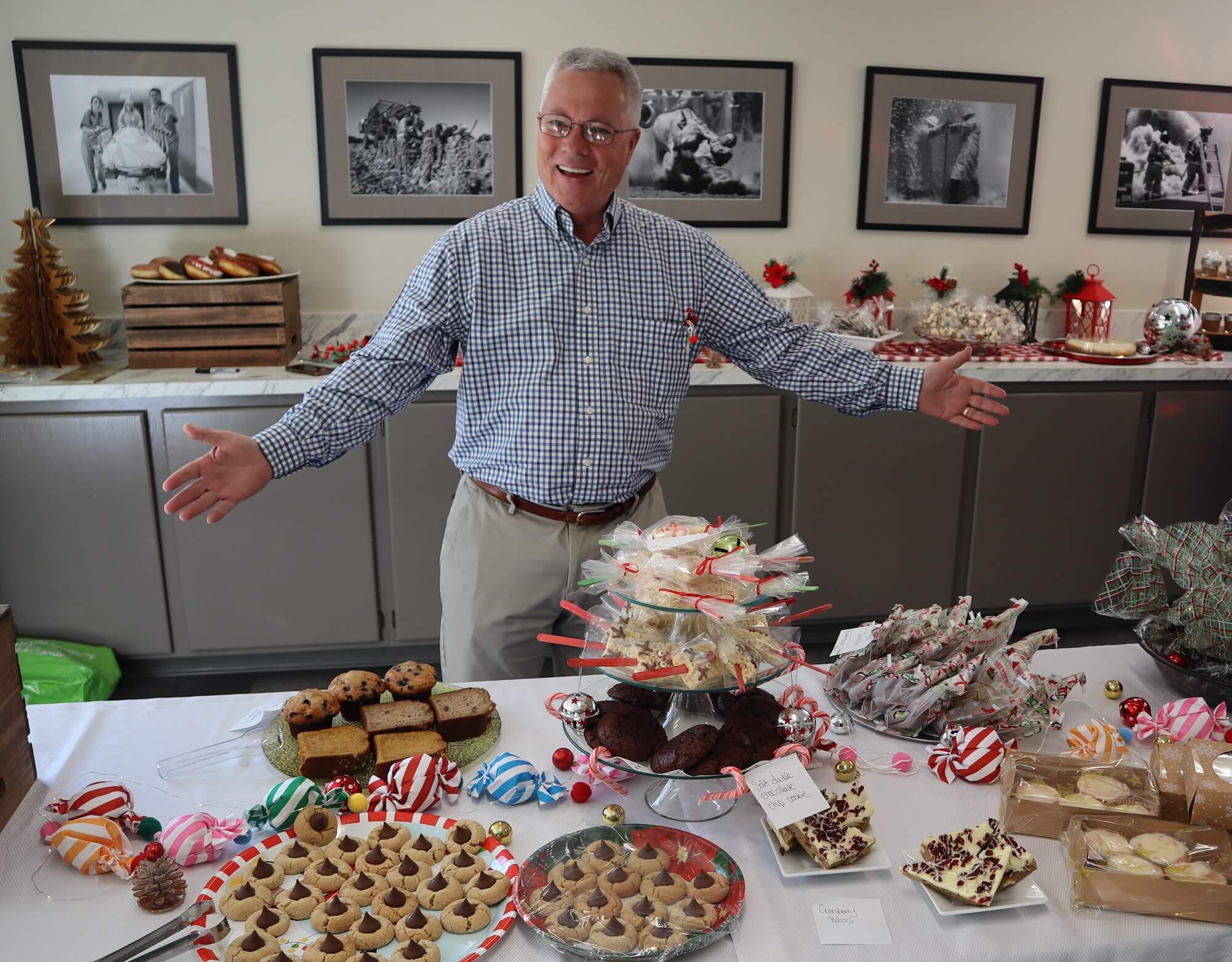 Deacon Warren Hoy smiling standing behind a table full of baked goods.