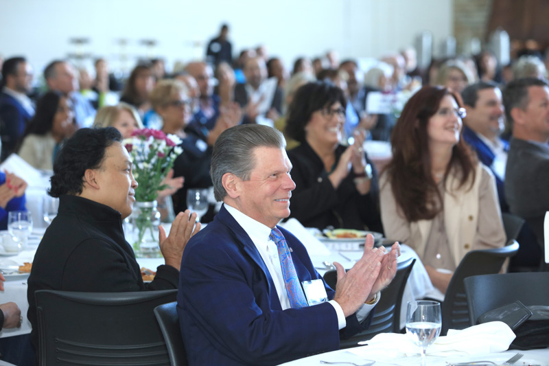 Crowd sitting at tables, clapping