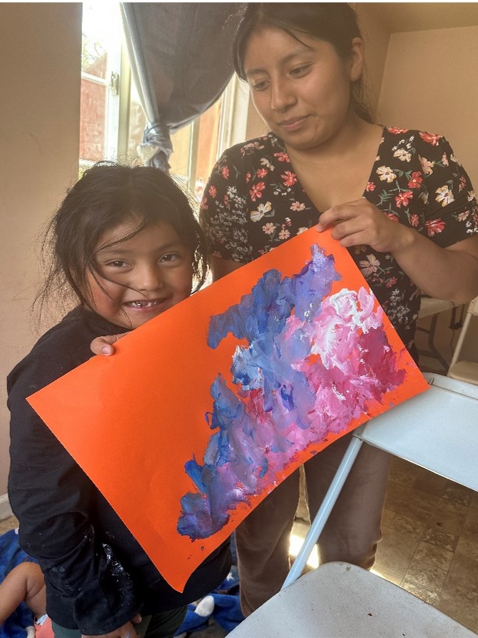 Claudia and a child showing off a painting