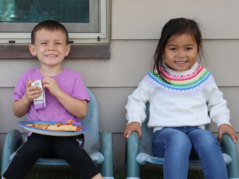 Two Preschool kids sitting smiling at the camera