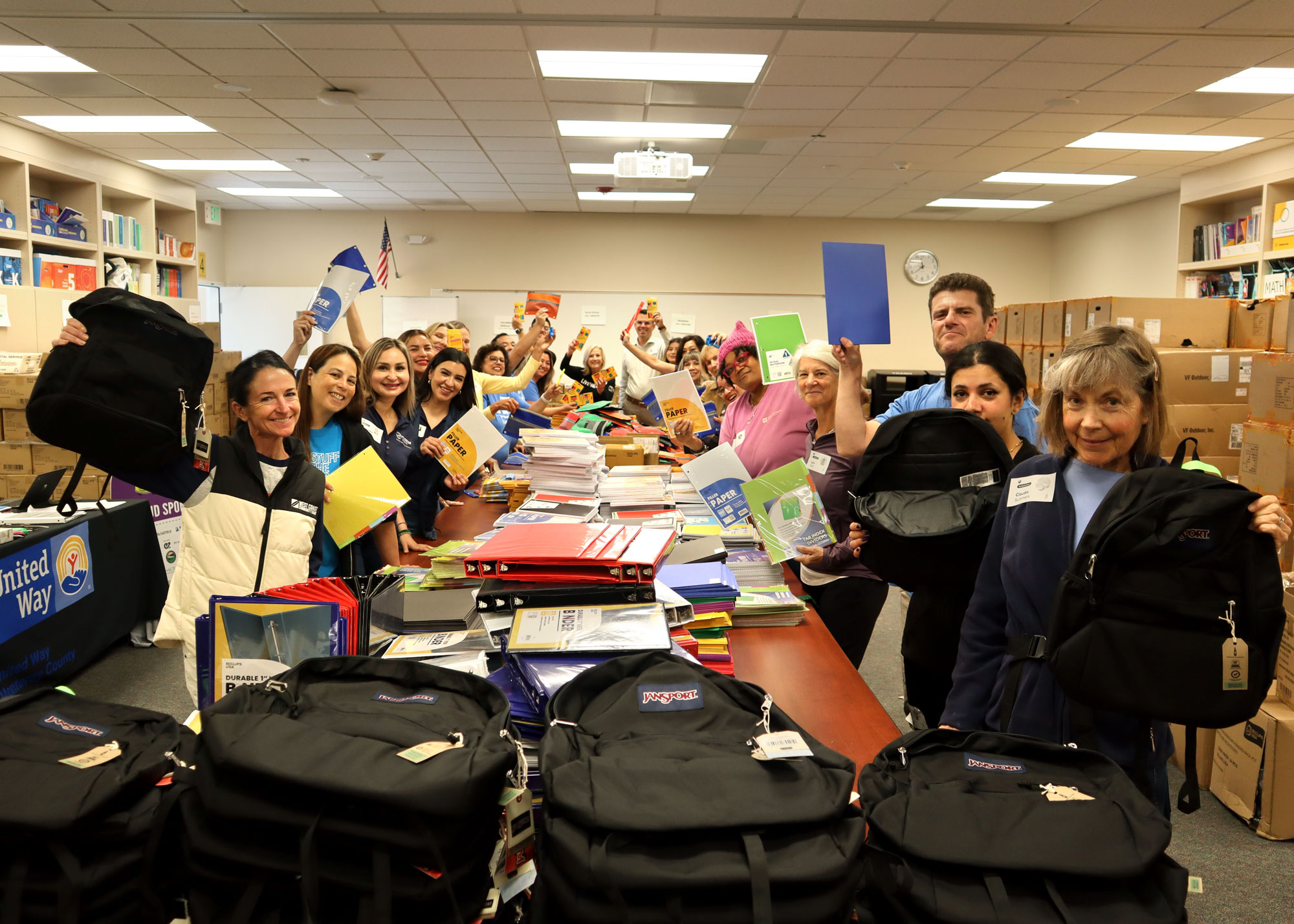 Group of volunteers holding up school supplies