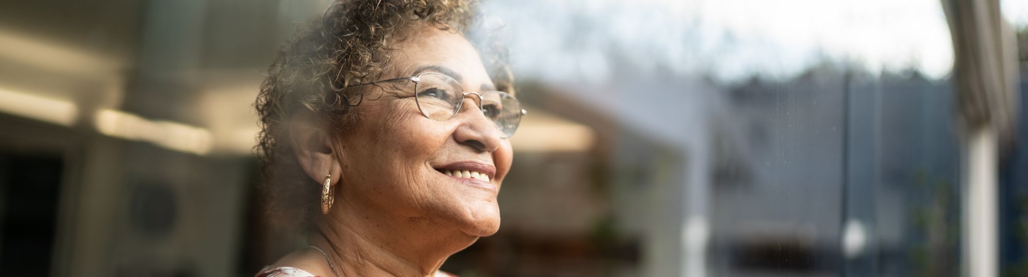 Older woman looking out a window smiling