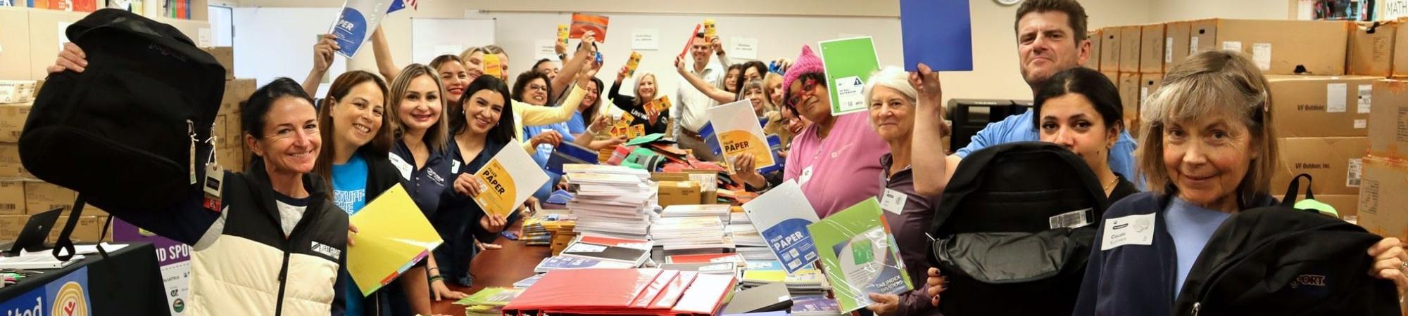 Volunteers holding up school supplies